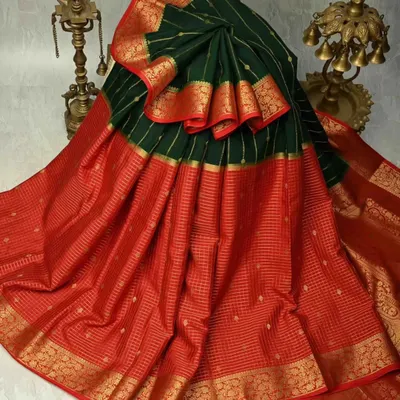 A classic Kanjivaram in a stunning combination of bottle green and red. The body features delicate gold checks, while the wide zari border adds a touch of bridal grandeur. This is a timeless piece for any silk connoisseur.