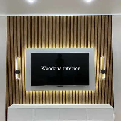 A beautiful TV unit design featuring a fluted wood panel background. The floating white console, backlit TV panel, and stylish wall sconces create a modern and elegant look.