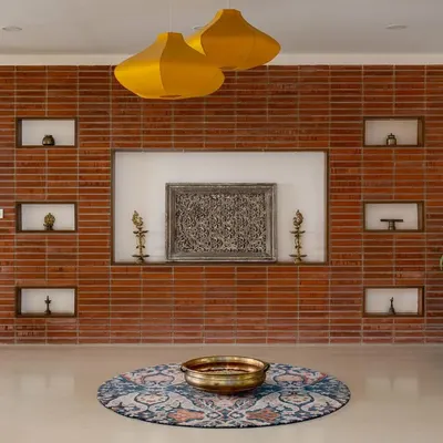 The journey into our 'Vasudhalayah' project begins with this stunning foyer. The wall is cloaked in wire-cut bricks with carved niches for family heirlooms, setting a warm, traditional, and personal tone for the home.