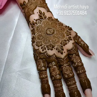 A classic bridal design featuring a large, intricate mandala on the back of the hand. The fingers are adorned with matching detailed patterns, creating a cohesive and traditional look.