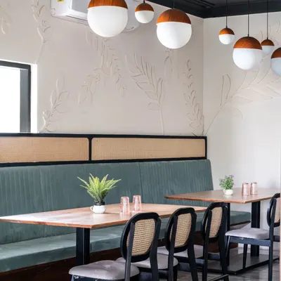 Every restaurant needs versatile spaces. I created this private dining niche for larger groups, using CNC-cut wood leaves on the wall to add a subtle, whimsical texture. The bleached wood tables and frosted glass pendants create a calm, complementary atmosphere.