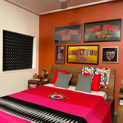 A bedroom makeover featuring my work. The wall displays a gallery of framed vintage ethnic embroidery, while the bed is dressed in a vibrant, hand-quilted throw. Many of these vintage materials are available for custom projects.