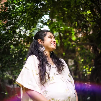 This is a portrait of pure joy. We used the natural garden light and a subtle lens flare to create an artistic, dreamy photo that captures the mother-to-be's happiness and excitement. This style of solo maternity portrait focuses on authentic emotion.