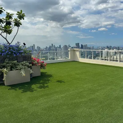 A beautiful rooftop terrace featuring a flawless artificial lawn overlooking the city. This installation provides a consistently green and clean surface, perfect for planters, outdoor furniture, and enjoying the view.