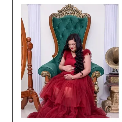Feel like a queen on your special day. This portrait features our stunning green throne chair and a dramatic red tulle gown. It's a powerful and regal solo shot, celebrating the strength and beauty of motherhood.