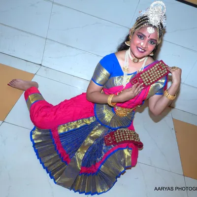 A dynamic, high-angle shot of a Bharatanatyam dancer in a traditional pose. This perspective highlights the beautiful flare of the costume and the dancer's graceful form.