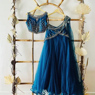A beautiful teal blue Indo-Western lehenga with intricate beadwork, displayed on our rustic bamboo ladder. This outfit is available to rent for your next shoot.