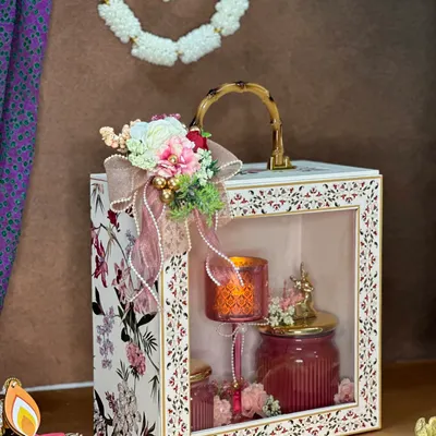 This exquisite hamper is a true style statement for your Diwali gifting. The elegant box with a window display contains a lit candle and beautiful jars, making it a luxurious and practical gift that also complements home decor.