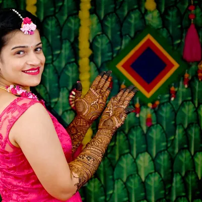 A beautiful bride showing off her full-sleeve mehendi. The rich, dark paste promises a fantastic stain, and her smile says it all.