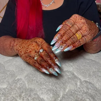 The ultimate bridal nails. These long, stiletto extensions feature a soft blue and white ombre, adorned with crystals and designed to complement intricate henna.
