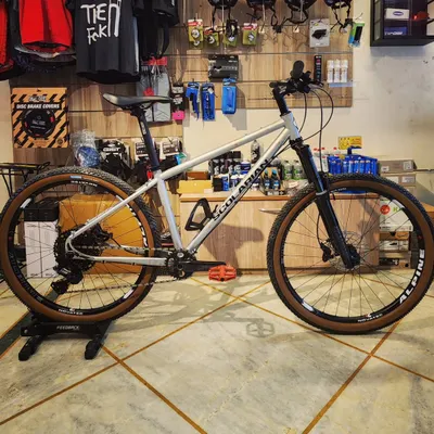 A full profile of the 'Contrarian', a custom-built hardtail MTB. This build features a Scolarian frame made with Columbus Zona steel tubes, a RockShox suspension fork, and a 1x10 Microshift Adventx drivetrain for simplicity and performance on the trail.
