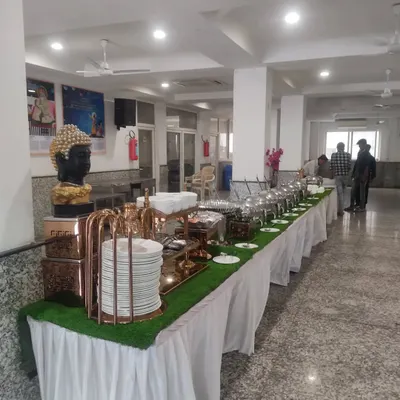 A clean and professional buffet setup for a corporate lunch. We use a long table with crisp white skirting, an artificial grass runner for a touch of green, and elegant chafing dishes to keep the food warm.