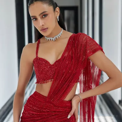 This show-stopping red drape saree from the Élan ‘24 collection is the epitome of modern glamour. The fluid drape, daring slit, and embellished bustier are designed for the woman who owns the room.