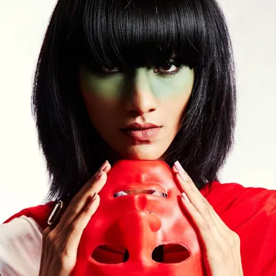 A close-up of a high-concept look featuring a sharp black bob wig and green color-blocking on the skin. This kind of work is about creating a memorable character, not just a makeup look.
