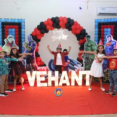 This Avengers-themed party for Vehant was all about assembling the heroes. The stage featured a red carpet, large marquee letters spelling his name, and life-sized cutouts of characters like Hulk and Superman against a balloon arch.