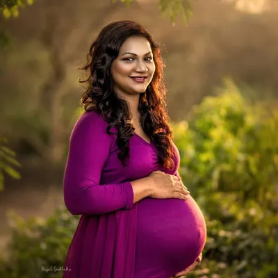Bathed in the warm glow of the setting sun, this mother-to-be radiates pure joy. The golden hour light in this outdoor portrait perfectly highlights her beautiful baby bump and happy smile.