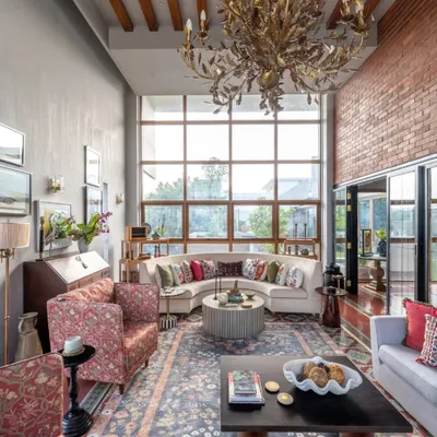 A grand living room in our Dhaka project, where we balanced a soaring ceiling and massive window with cozy, curated seating. The space is filled with custom furniture, a statement chandelier, and an exposed brick wall, creating a look that is both contemporary and rich with heritage.