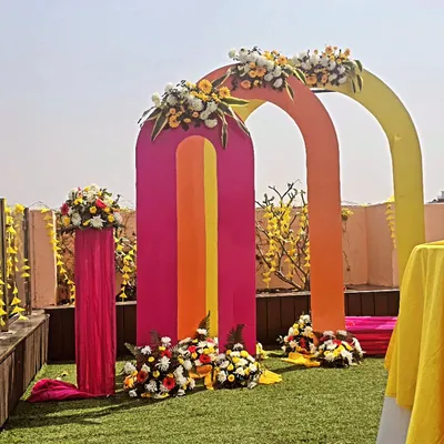 A modern take on haldi decor with a series of colorful arches. This setup is perfect for an outdoor lawn, adding a playful and artistic touch to your daytime ceremony.