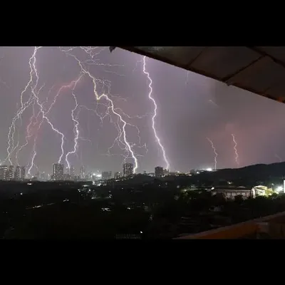 A panoramic view of the lightning storm over the Mumbai skyline, taken from our balcony. This wide shot shows the immense scale of the storm as multiple bolts strike across the city and hills.