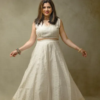 A joyful and elegant portrait. Her beautiful white ethnic dress and open, welcoming posture create a feeling of warmth and grace against a simple, textured studio background.