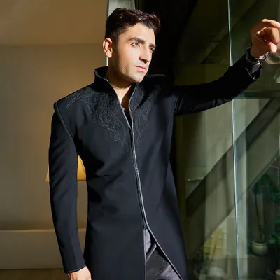 This black Indo-Western piece is all about modern drama. The longline jacket features intricate, tonal hand-embroidery around the high collar and a bold zipper front, creating a sharp, contemporary silhouette.