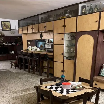 **BEFORE:** A living area from the 1980s, filled with heavy, dark wood cabinetry, a built-in bar, and terrazzo flooring, which made the space feel dated and compartmentalized.