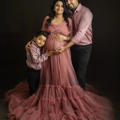 A gorgeous family maternity portrait. The flowing pink gown and the loving embrace of her family make this shot so special.