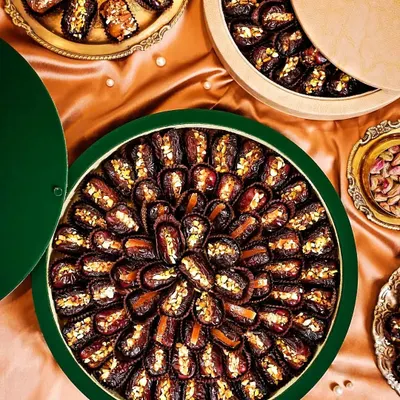 A luxurious flatlay of gourmet stuffed dates, arranged in beautiful circular patterns. The rich colors of the dates against the satin green fabric create an opulent and elegant visual.