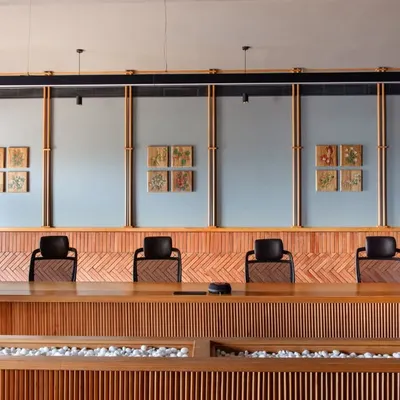 The spacious boardroom at Anthea Pharma, designed for 20 people, features a vaulted concrete ceiling for acoustics and walls clad in brick from Kerala. The design blends Indian craftsmanship with locally sourced materials for an elegant and warm atmosphere.