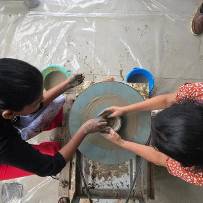 This is where it all starts. A top-down view of two people working together on the pottery wheel, learning to center the clay. It's a true team effort.