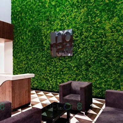 A full-view of a reception area transformed by a floor-to-ceiling preserved moss wall. This installation immediately establishes a biophilic and high-end atmosphere for visitors, complemented by the geometric flooring and modern furniture.