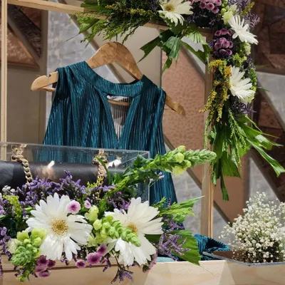 A close-up of one of our trousseau packing designs. We used a wooden frame to hang this teal pleated top, with a clear acrylic box to protect a luxury handbag below, all adorned with fresh white gerberas and purple statice.