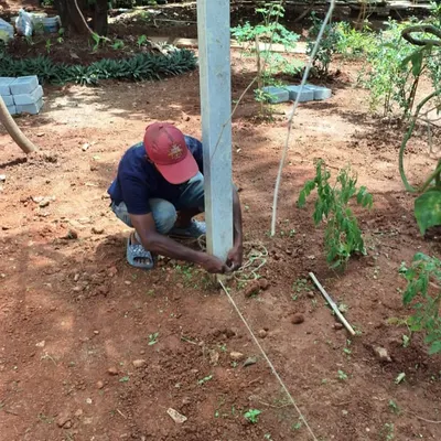 The foundation of a new landscape. A team member is seen setting up a post and guide lines in a dirt yard, the first step in structuring the garden layout.