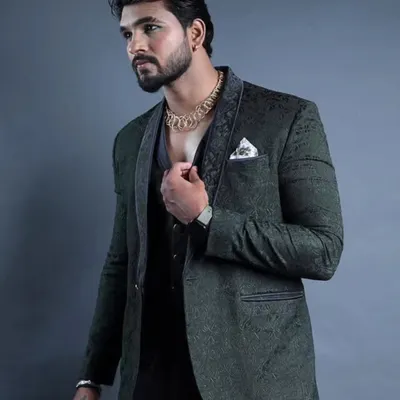 This dark green three-piece suit features a subtle, textured pattern and a contrasting lapel. It's a sophisticated and modern choice for a reception or formal party.