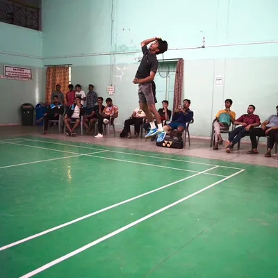 A player captured at the peak of his jump, demonstrating excellent form and height before striking the shuttlecock.