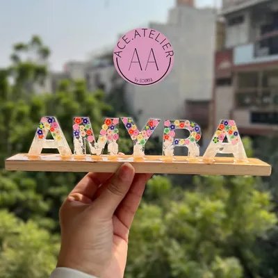 A beautiful custom name stand for 'Amyra', filled with colorful flowers and set on a wooden base. This makes a wonderful, personalized decoration for a child's room.