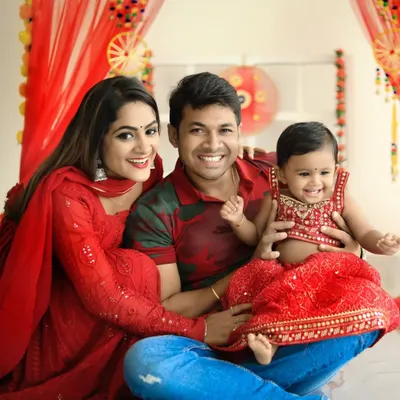 Celebrating Diwali with the whole family. This festive portrait captures a beautiful moment with mom, dad, and their little one, all dressed in coordinated red outfits.