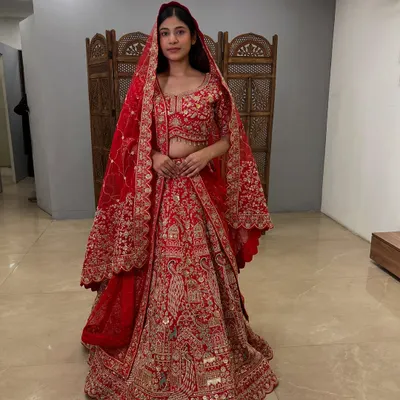 The complete bridal look. This classic red lehenga with heavy gold embroidery is a timeless choice for the main wedding ceremony.