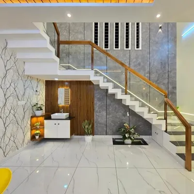 We specialize in making functional use of every corner. Here, we designed a modern staircase with a glass railing and built a compact vanity unit underneath, complete with a sink, cabinet, and display shelves. This is a great way to add utility to the space under a staircase.