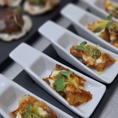 Artfully presented appetizers in individual ceramic spoons. This serving style is perfect for mingling, allowing guests to enjoy complex flavors like this toasted bread with cheese and pesto without any hassle.