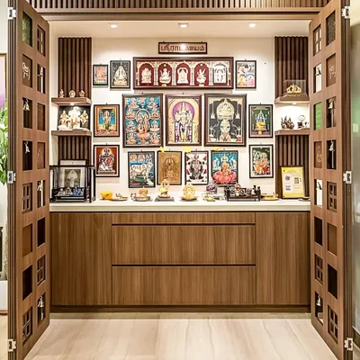 An elaborate pooja room with custom wooden doors that open to reveal a multi-tiered display for idols and frames. The unit includes base cabinets for storing religious items.