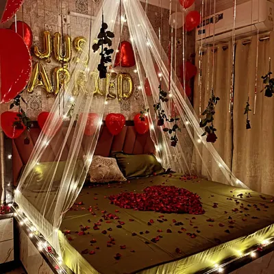 A closer look at the 'Just Married' bed canopy setup. You can see the detail of the fairy lights woven into the sheer fabric and the hanging black roses, which add a unique touch to the classic red and white theme.