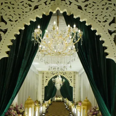 A majestic entrance for a Sufi-themed reception, featuring grand white arches with intricate jali work and rich, dark green velvet curtains.