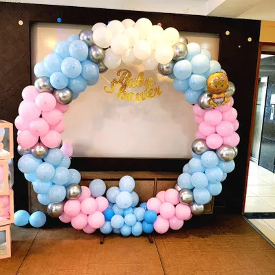 A classic baby shower decoration with a pink and blue balloon ring. This setup is perfect for gender reveal parties and includes themed props like "BABY" blocks.