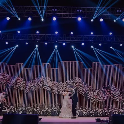 A wide shot of a spectacular Sangeet stage with dramatic lighting and floral decor. We capture the grandeur of your event design.