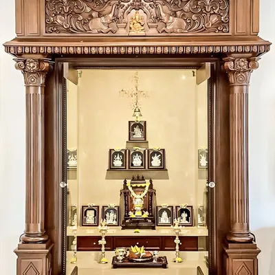 This magnificent pooja room entrance is a testament to classic temple architecture, designed to be the spiritual heart of the home. We incorporated robust, intricately carved wooden pillars and a traditional header featuring Gajalakshmi motifs, creating a grand and auspicious entryway.