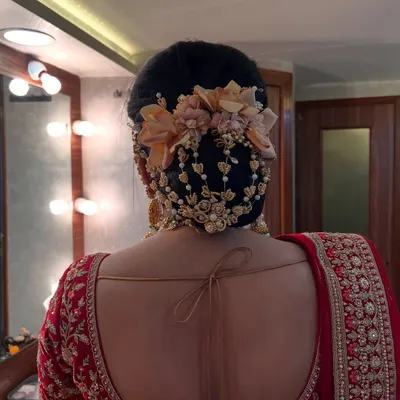 A close-up of a royal bridal transformation, focusing on the intricate floral bun. We used a combination of fresh flowers and delicate pearl accessories to create this elegant and timeless hairstyle.