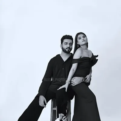 A stylish black and white studio portrait of a couple. The composition and posing create a modern, high-fashion look.