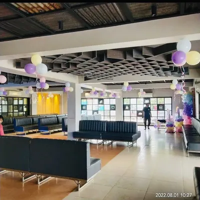 A wide view of a restaurant space decorated for a baby shower. I used pastel-colored balloon bunches hanging from the ceiling to add a soft and celebratory touch to the venue.