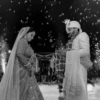 A powerful black and white shot of the Varmala exchange. The dramatic lighting and surrounding fireworks create a timeless and unforgettable image of this pivotal wedding moment.